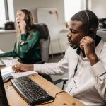 Equipe de atendimento ao consumidor trabalha em computadores e atende ligações usando headsets.