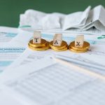 Documentos fiscais, recibos e moedas sobre uma superfície, representando contabilidade e finanças públicas.