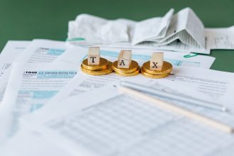 Documentos fiscais, recibos e moedas sobre uma superfície, representando contabilidade e finanças públicas.