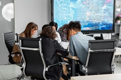 Equipe diversa reunida em um escritório moderno, colaborando diante de uma tela digital.