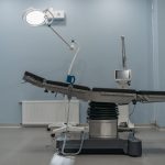 Sala de cirurgia moderna e vazia, com mesa cirúrgica e equipamentos médicos.