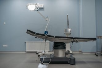 Sala de cirurgia moderna e vazia, com mesa cirúrgica e equipamentos médicos.