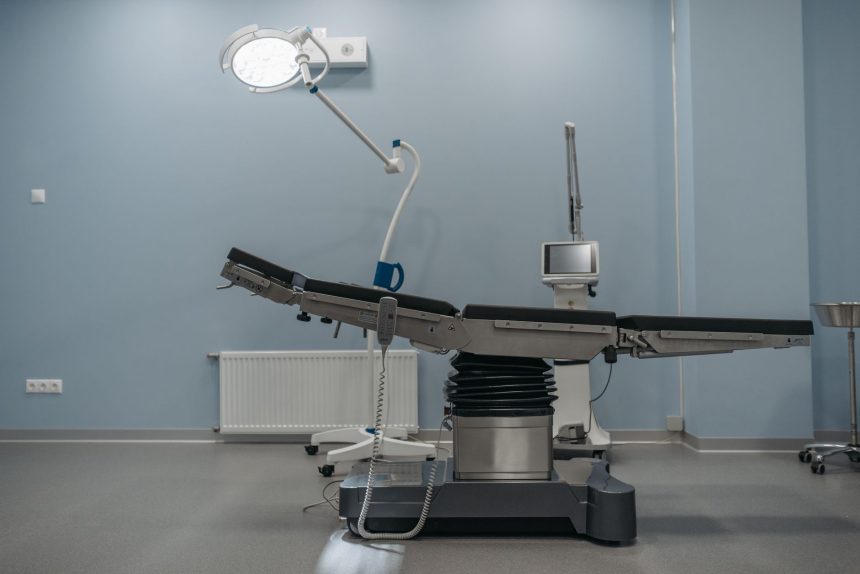 Sala de cirurgia moderna e vazia, com mesa cirúrgica e equipamentos médicos.