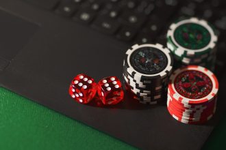 Fichas de cassino e dados sobre uma superfície escura, em referência a apostas e jogos de azar online.